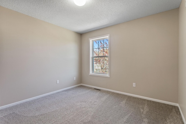 carpeted spare room featuring baseboards and a textured ceiling
