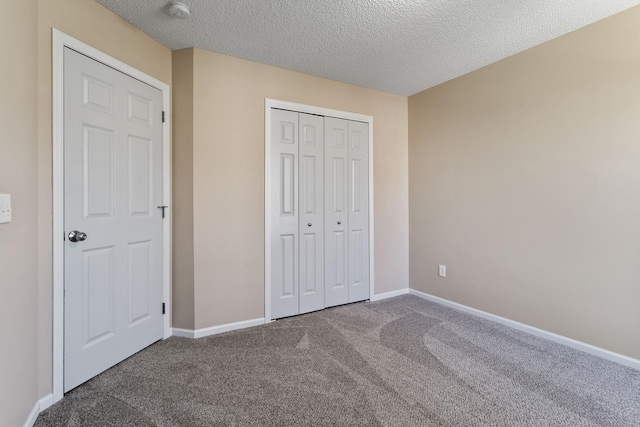 unfurnished bedroom with carpet floors, a textured ceiling, a closet, and baseboards