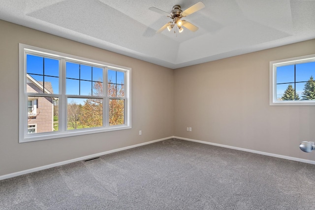 carpeted empty room with baseboards, a ceiling fan, and a raised ceiling