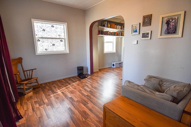 living area with baseboards, arched walkways, and wood finished floors