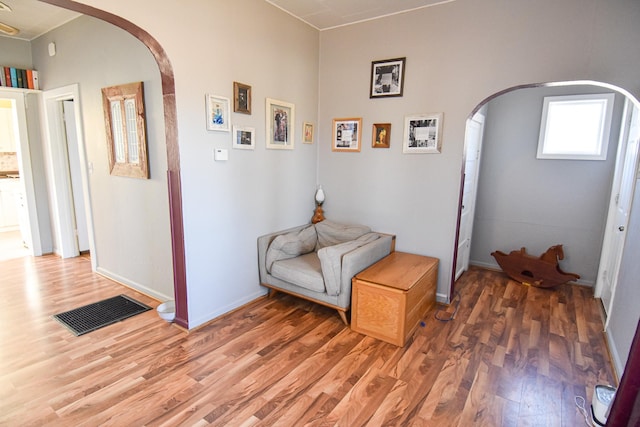 living area with light wood-style flooring, arched walkways, and baseboards