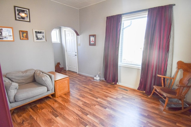 living area featuring arched walkways, baseboards, visible vents, and light wood-type flooring