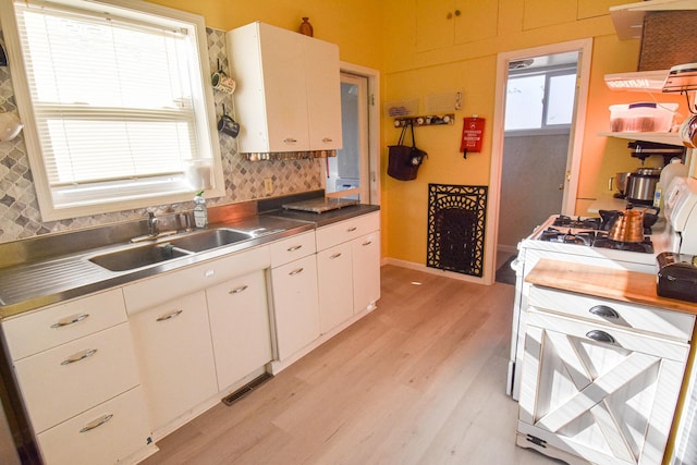 kitchen featuring light wood finished floors, a sink, stainless steel counters, and visible vents
