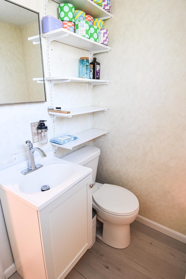 bathroom with toilet, vanity, and wood finished floors