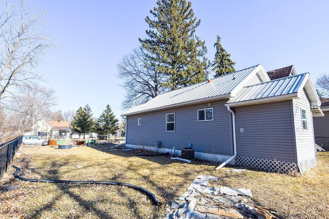 back of house with metal roof, central air condition unit, and fence