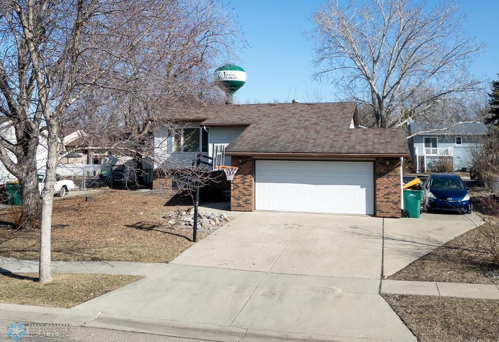 view of front of property featuring brick siding, roof with shingles, an attached garage, and concrete driveway