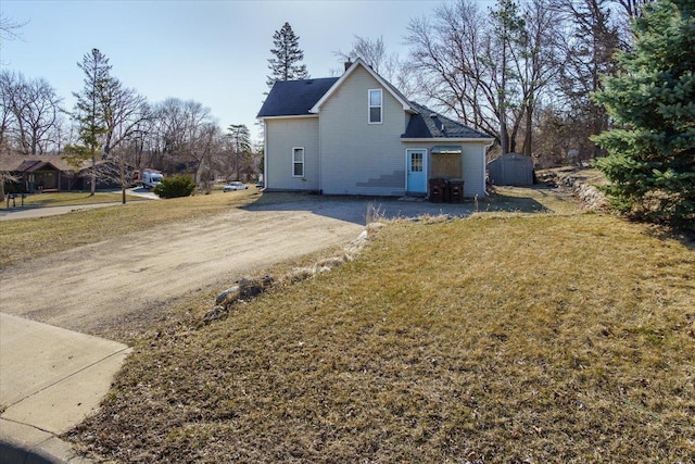 exterior space with a lawn, a storage shed, an outbuilding, and dirt driveway