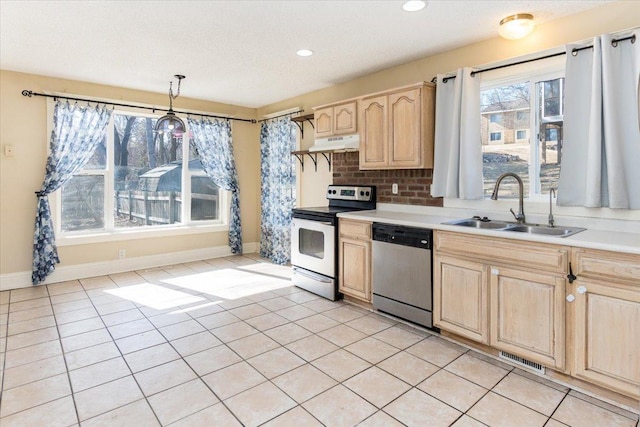 kitchen featuring a sink, light countertops, light brown cabinetry, under cabinet range hood, and stainless steel appliances