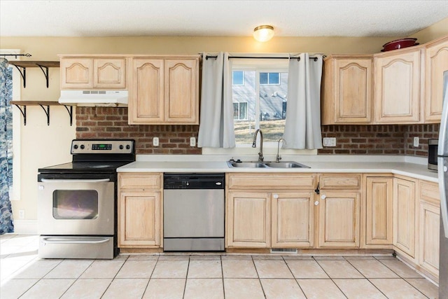 kitchen with light tile patterned floors, light brown cabinetry, appliances with stainless steel finishes, under cabinet range hood, and a sink