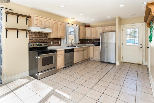kitchen with a sink, light countertops, appliances with stainless steel finishes, light brown cabinetry, and under cabinet range hood