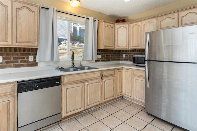 kitchen featuring stainless steel appliances, light tile patterned floors, a sink, and light brown cabinetry