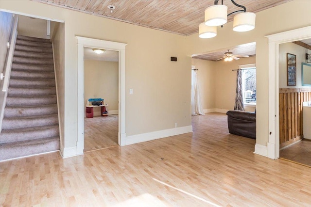 unfurnished living room with light wood-style floors, a ceiling fan, wood ceiling, stairs, and baseboards