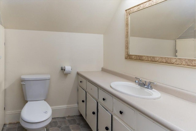 bathroom featuring toilet, vanity, baseboards, and vaulted ceiling