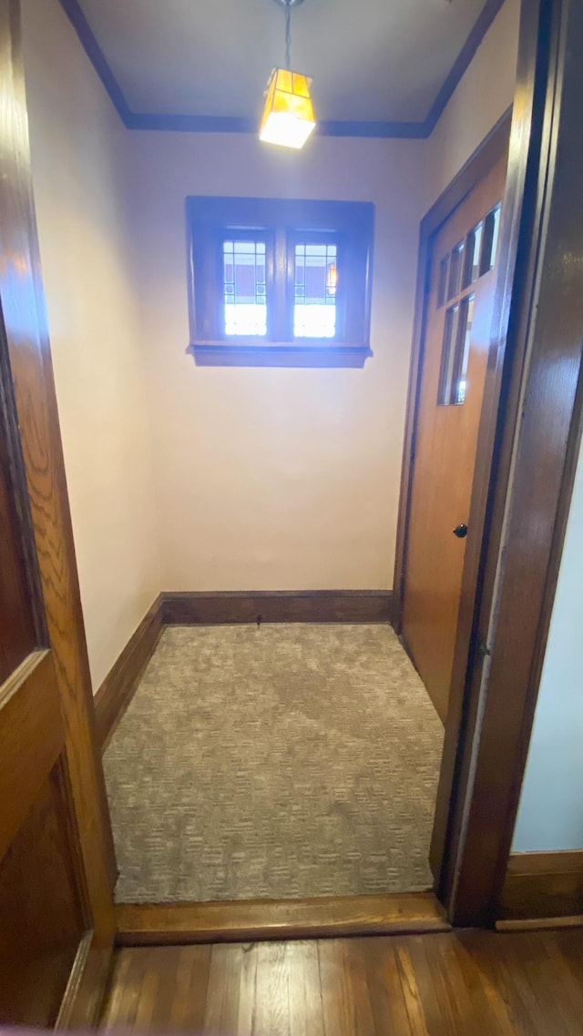 hallway featuring hardwood / wood-style floors, crown molding, and baseboards