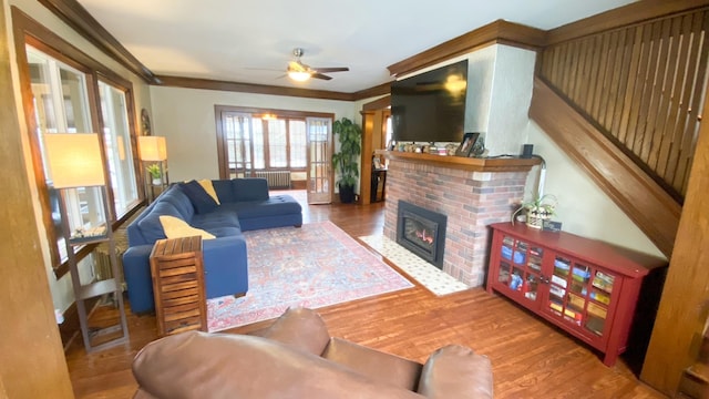 living room with ornamental molding, ceiling fan, wood finished floors, and a fireplace