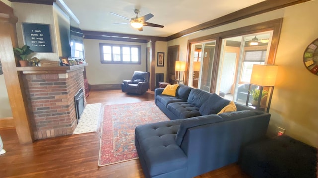 living room with a ceiling fan, baseboards, wood finished floors, and a fireplace