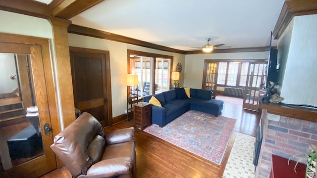 living area with wood finished floors, a ceiling fan, and ornamental molding