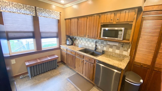 kitchen with a sink, stainless steel appliances, baseboards, radiator, and ornamental molding
