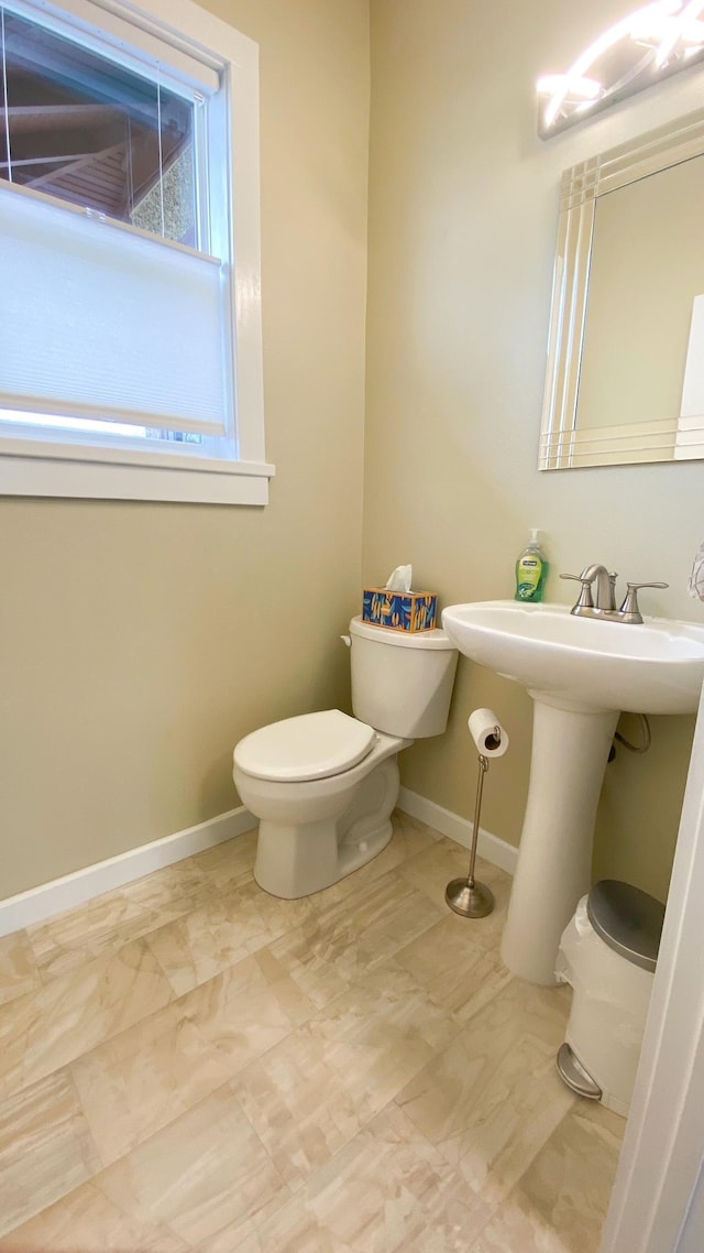 bathroom with a sink, toilet, and baseboards