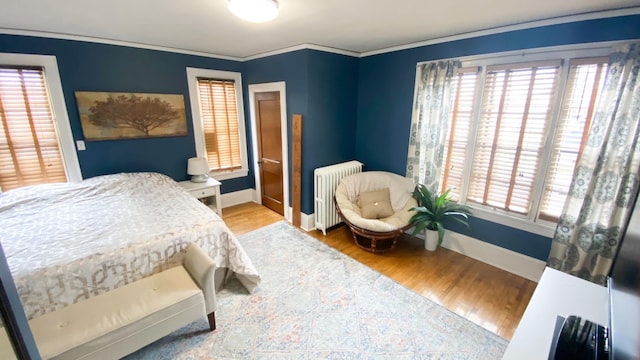 bedroom featuring crown molding, radiator heating unit, wood finished floors, and baseboards