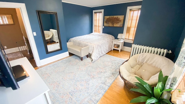 bedroom featuring baseboards, radiator heating unit, radiator, and wood finished floors
