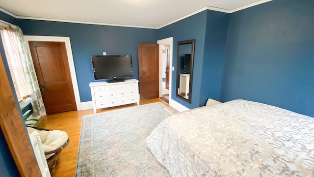 bedroom with crown molding, wood finished floors, and baseboards