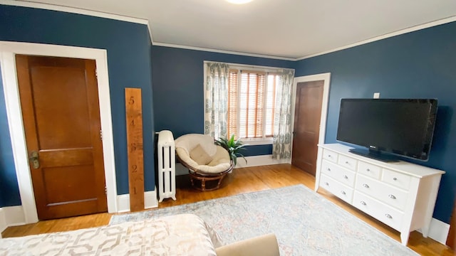 living area with radiator, wood finished floors, crown molding, and baseboards