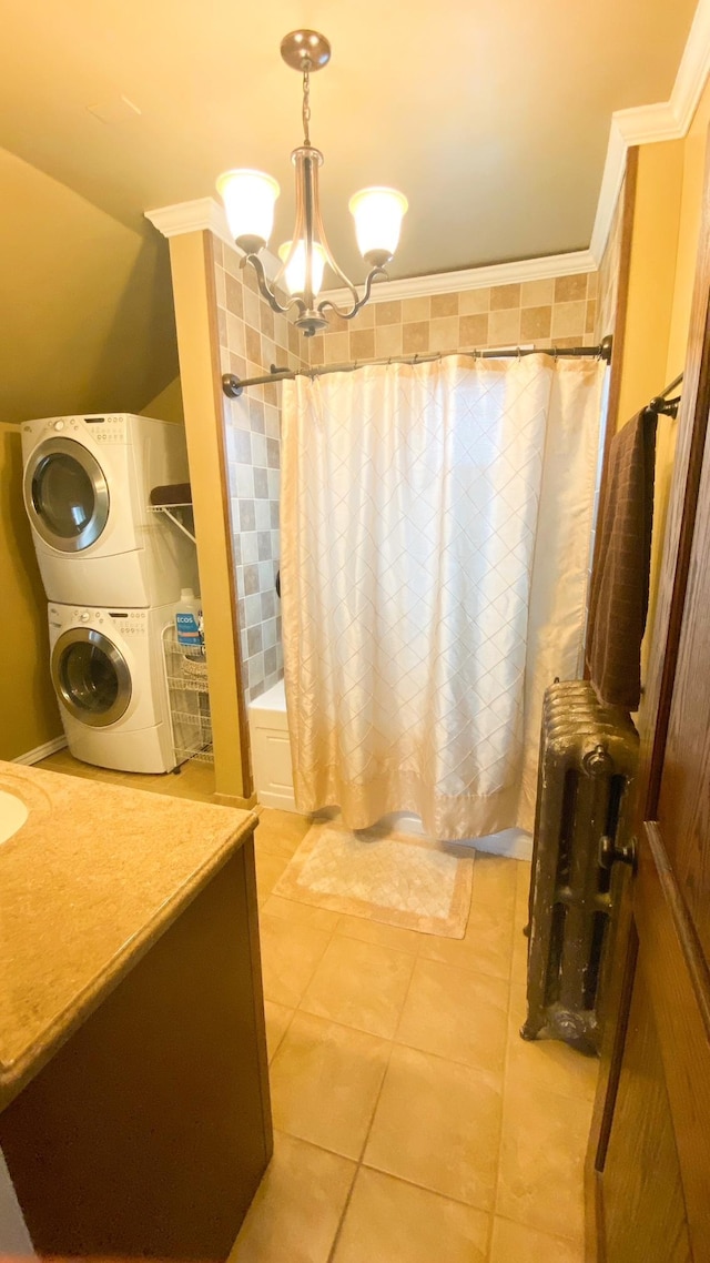 full bathroom featuring stacked washing maching and dryer, vanity, a chandelier, tile patterned floors, and ornamental molding