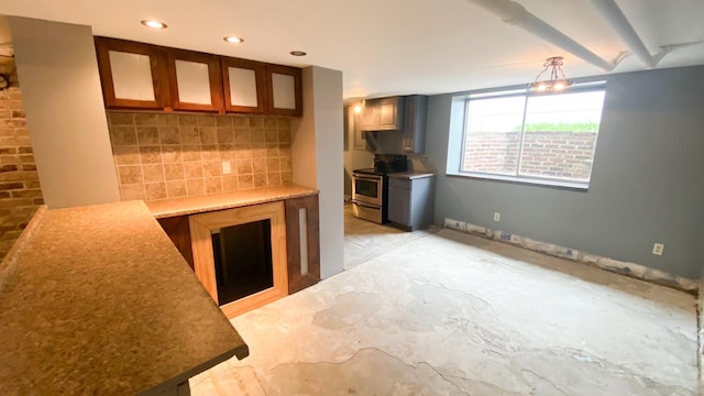 kitchen featuring a wood stove, backsplash, glass insert cabinets, and stainless steel range with electric cooktop