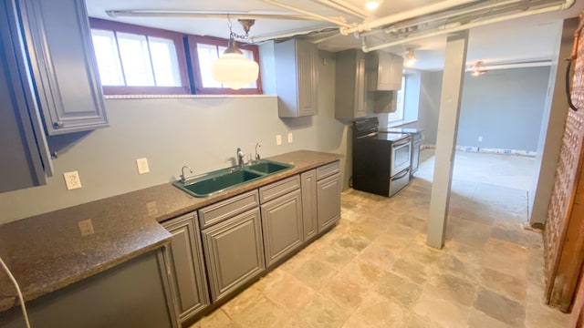 kitchen featuring electric stove, dark stone countertops, stone finish floor, and a sink