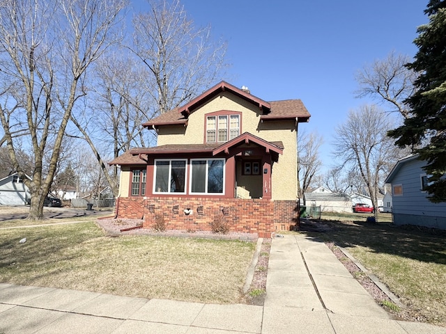 view of front of home featuring fence, roof with shingles, a front lawn, and brick siding