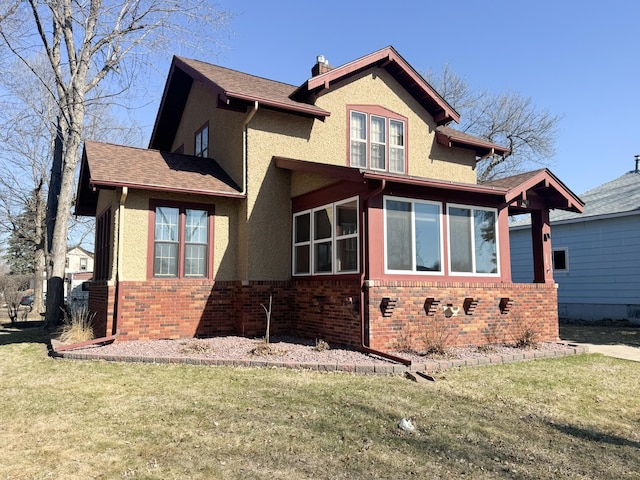 view of property exterior with a lawn, stucco siding, and brick siding