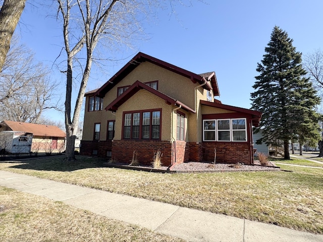 view of side of property with a lawn, stucco siding, and brick siding