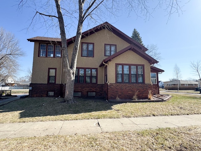 traditional-style house with a front lawn, stucco siding, and brick siding