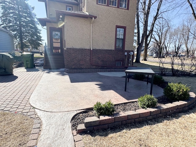 back of property with brick siding, stucco siding, and a patio area