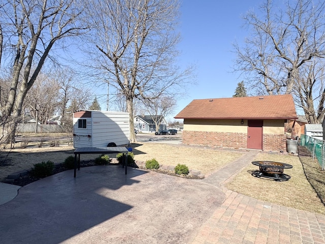 view of patio featuring fence, a storage shed, an outdoor fire pit, and an outbuilding