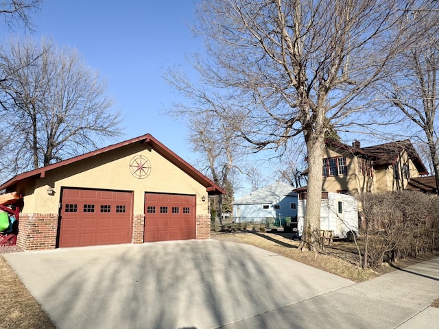 view of home's exterior with stucco siding, driveway, brick siding, and a garage