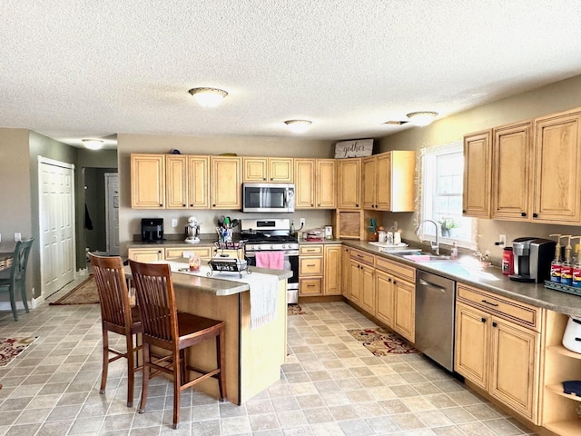 32661 County Road 16, Ross, MN 56751 - kitchen featuring stainless steel appliances, a sink, a kitchen breakfast bar, a kitchen island, and a textured ceiling