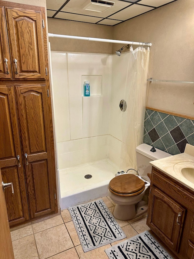 full bathroom featuring a shower stall, toilet, tile patterned floors, and tile walls