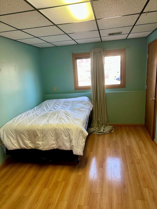 bedroom with a paneled ceiling, wood finished floors, and baseboards