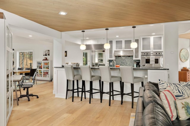 285 Leaf St, Orono, MN 55356 - kitchen featuring oven, white cabinets, a breakfast bar, decorative backsplash, and light wood finished floors