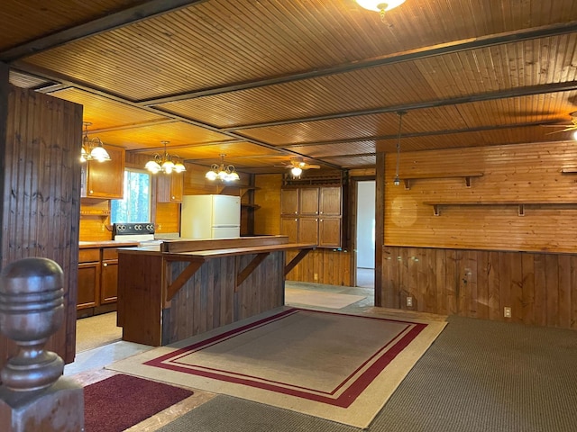 40884 Nature Ave, Fleming Twp, MN 56431 - kitchen featuring freestanding refrigerator, wooden walls, a chandelier, brown cabinetry, and a kitchen island