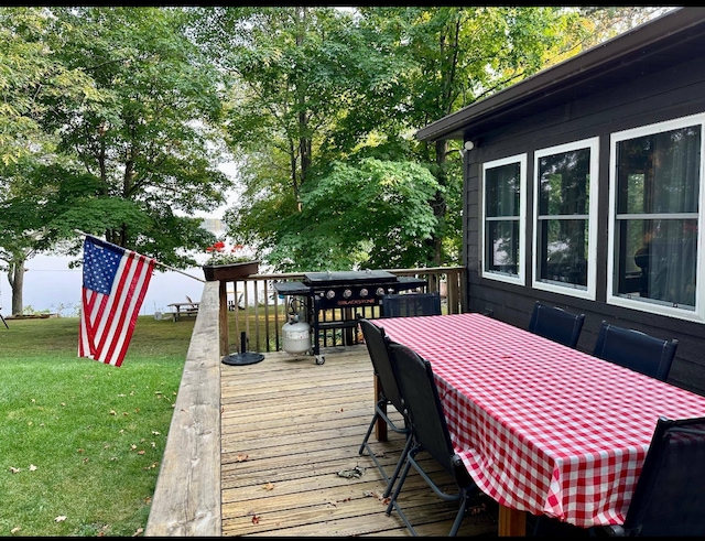 38985 337th Ln, Aitkin, MN 56431 - wooden terrace featuring outdoor dining space, a lawn, and a grill