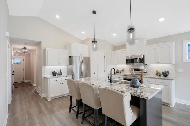 10052 177th Cir NW, Elk River, MN 55330 - kitchen with white cabinets, a sink, appliances with stainless steel finishes, a kitchen breakfast bar, and lofted ceiling