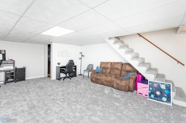 living area featuring carpet flooring, a drop ceiling, baseboards, and stairs