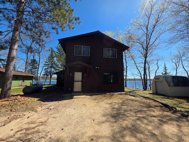 view of front facade with a storage shed, an outdoor structure, and a water view