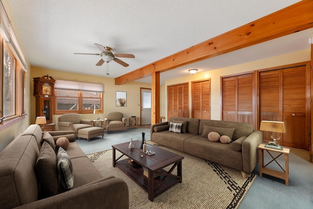 living area with carpet floors, a ceiling fan, beamed ceiling, and a textured ceiling
