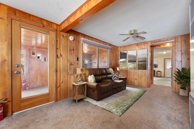 living room featuring wooden walls, carpet floors, a textured ceiling, and a ceiling fan