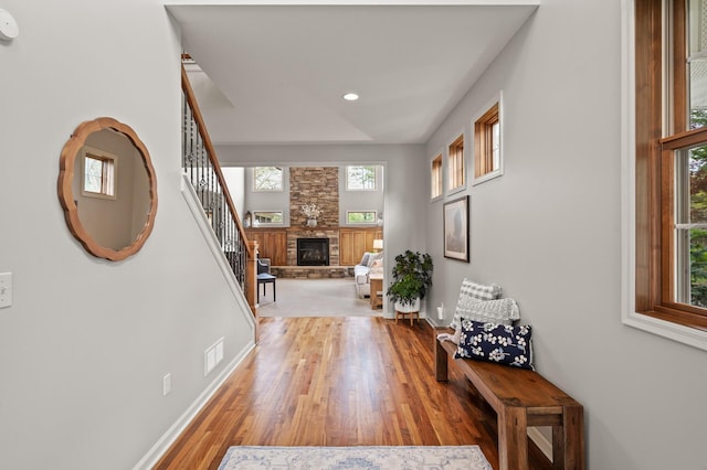 interior space with baseboards, a fireplace, stairway, visible vents, and light wood finished floors