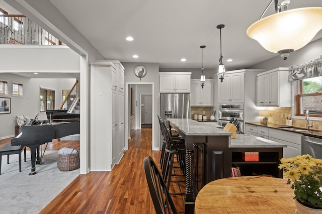 kitchen with recessed lighting, a center island, appliances with stainless steel finishes, wood finished floors, and a sink